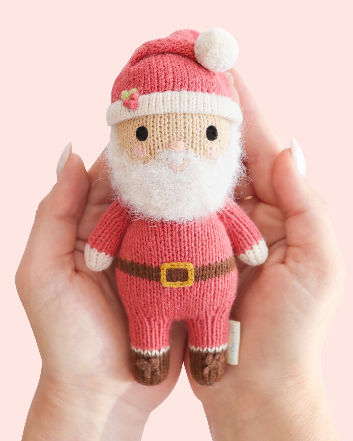 Soft plush Tiny Santa doll by Cuddle + Kind featuring a red hat, white beard, and cozy holiday outfit for children.