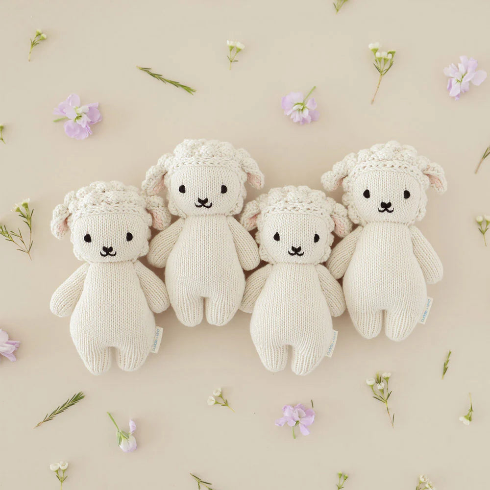 Soft baby lamb plush toy from Cuddle + Kind with gentle cream fur and embroidered facial features, perfect for cuddling.