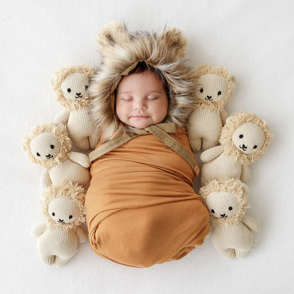 Soft plush baby lion toy by Cuddle + Kind featuring a realistic lion design with a gentle expression and detailed fur.