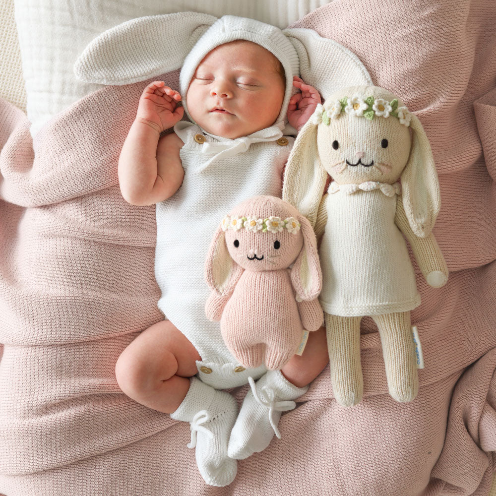 Soft pink baby bunny plush toy from Cuddle + Kind with ivory floral accents, designed for gentle cuddling and comfort.