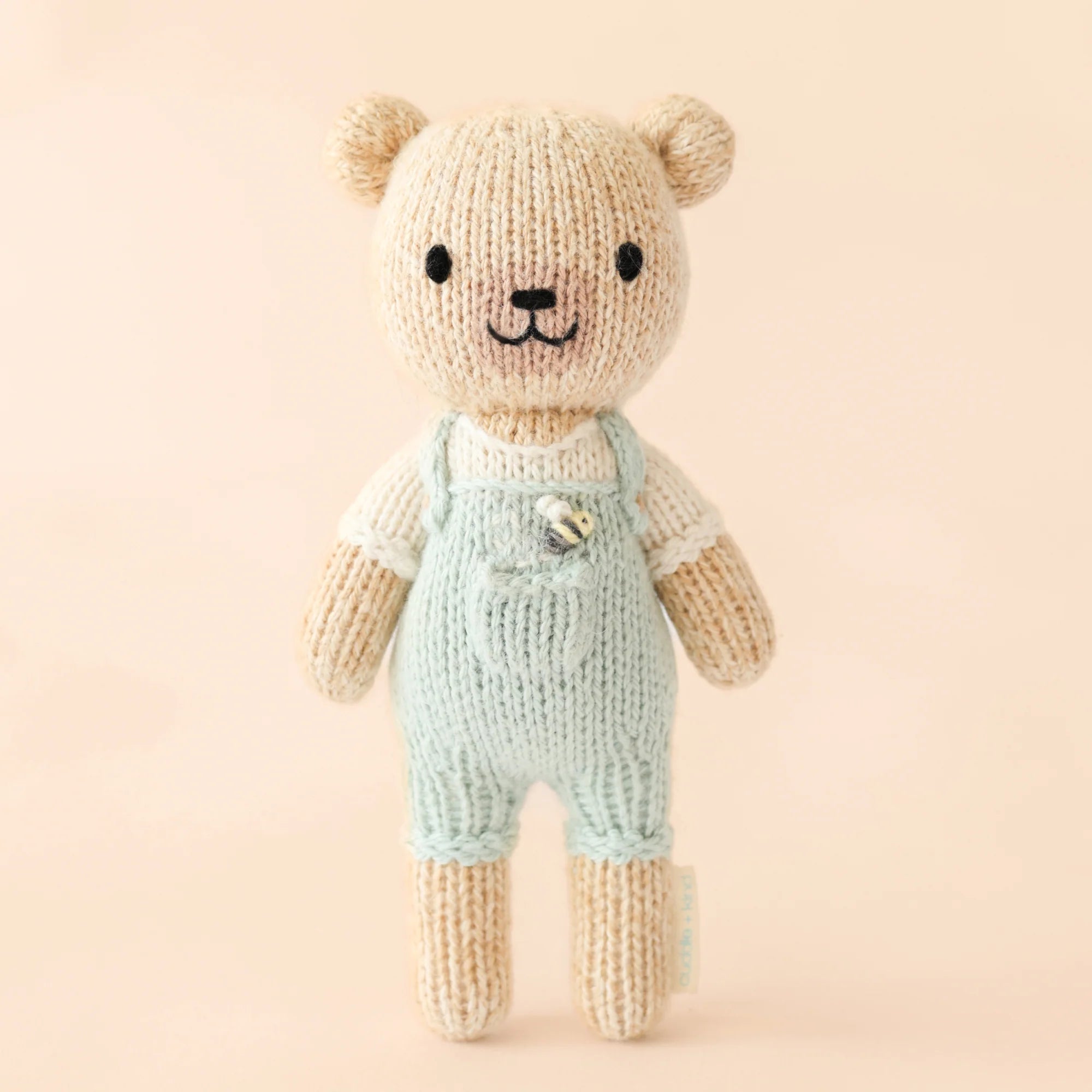 Tiny Charlie the Honey Bear from Cuddle + Kind, a soft plush toy with a honey-colored bear design perfect for cuddling.