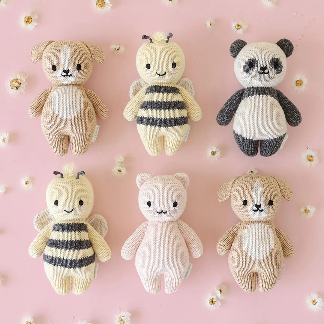 Soft plush baby puppy toy by Cuddle + Kind with gentle features and a cozy appearance, perfect for cuddling and play.