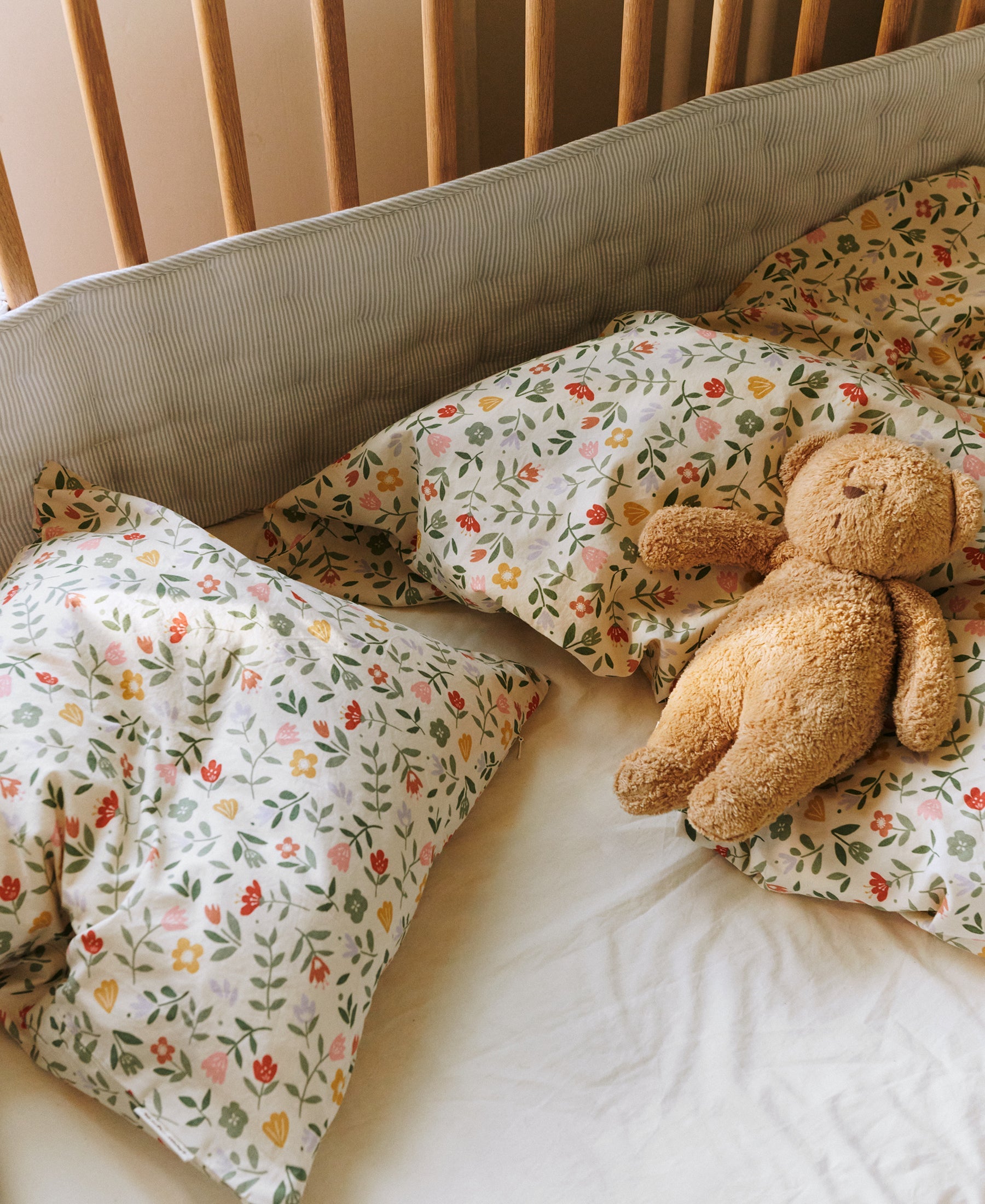 Dear April Nori Cot Bumper in Dew Stripe, fitted to a cot.
