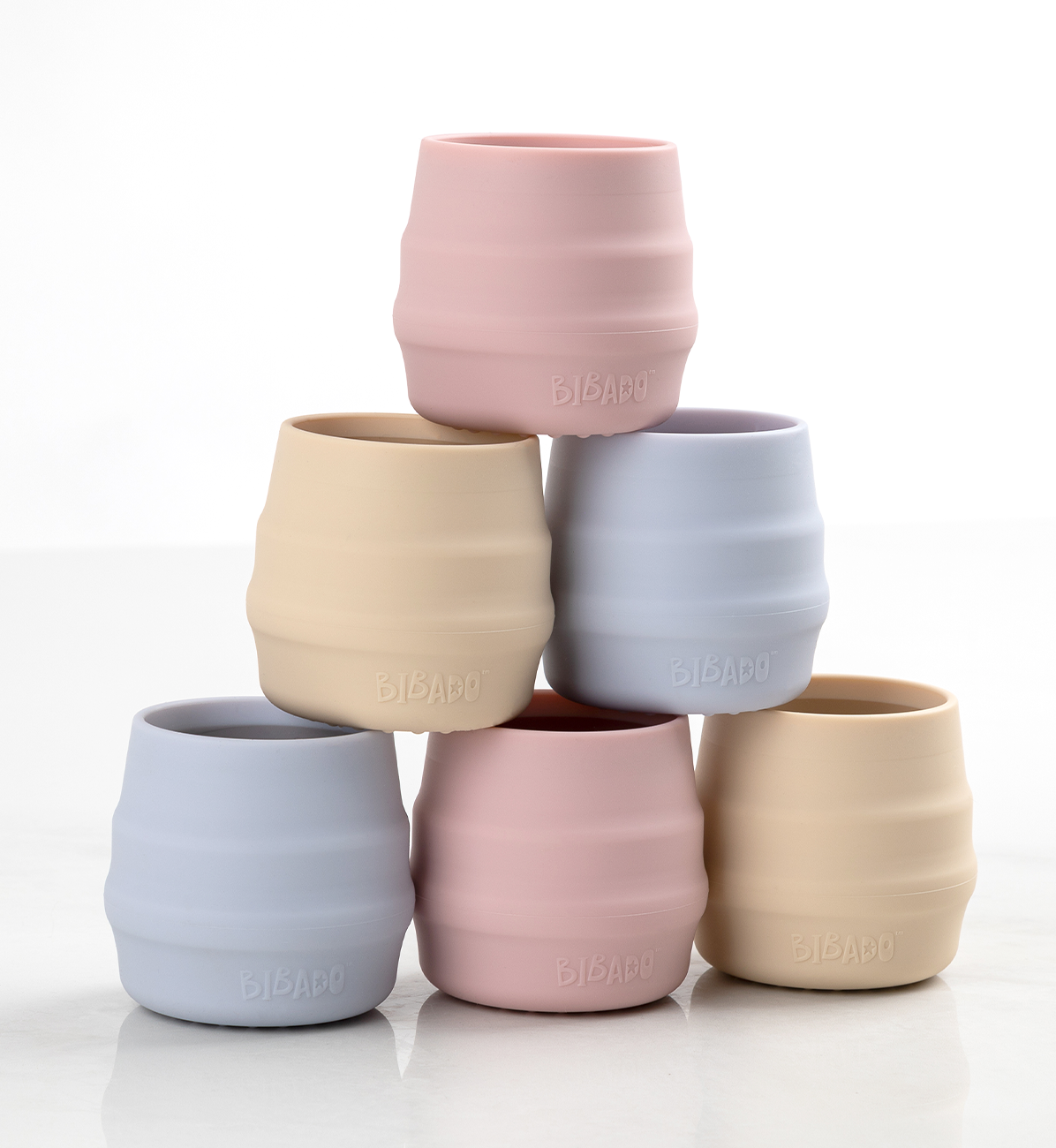 Two Bibado Sippit cups in blush pink with handles, designed for young children to help with self-feeding and drinking.