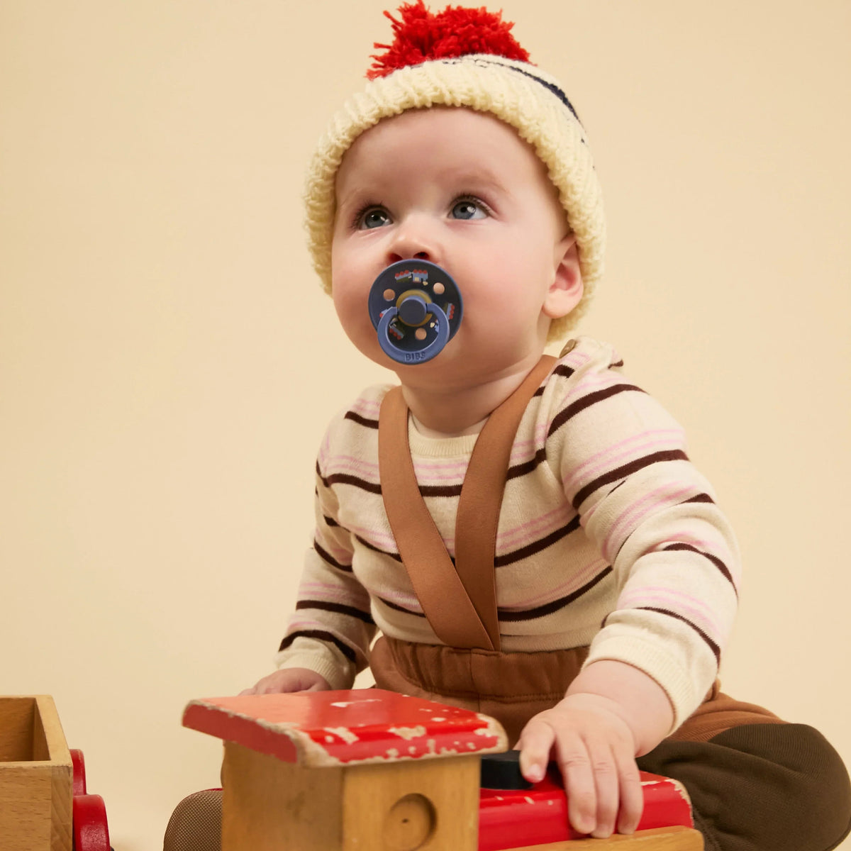Two BIBS Colour Pacifiers in baby blue and steel blue from Gnash, featuring holiday train design in a 2-pack accessories set.