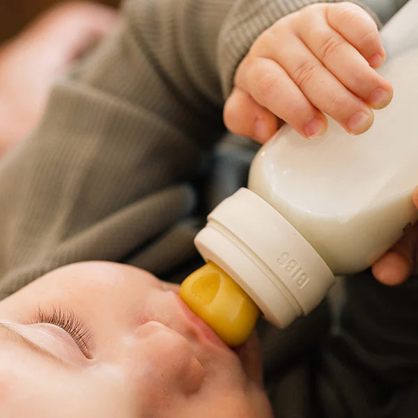 Baby being fed from a bottle with a yellow nipple