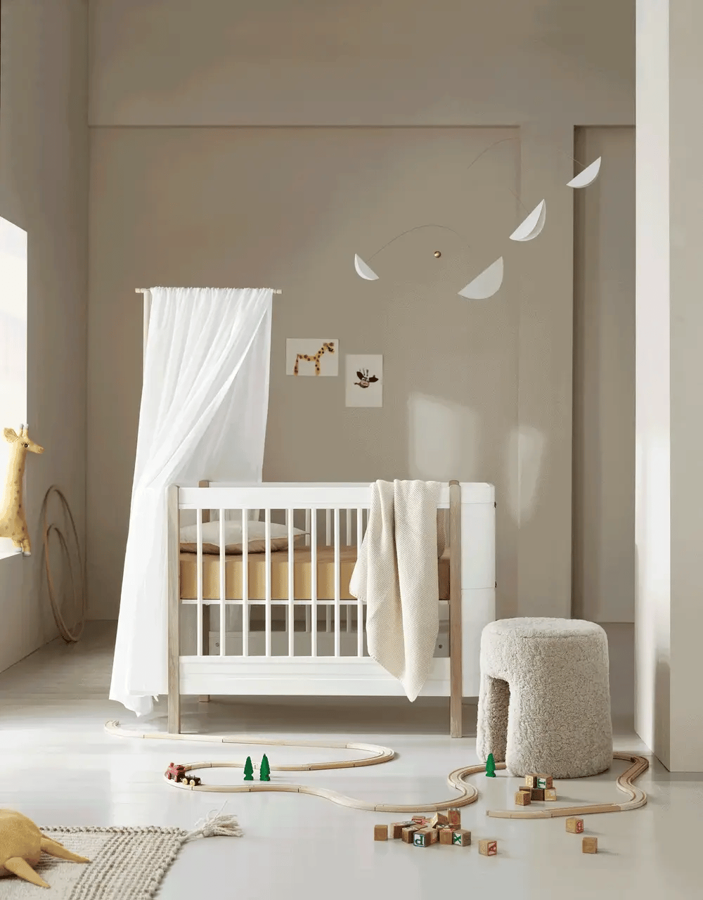 White and oak Wood Mini+ cot bed by Oliver Furniture, showcasing a compact, modern children's bed with safety rails and wooden finish.