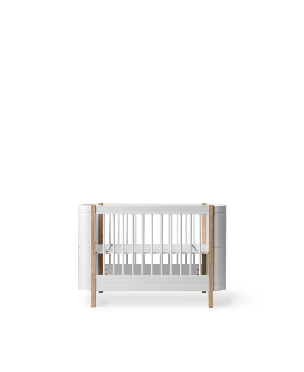 White and oak Wood Mini+ Cot Bed by Oliver Furniture, showcasing a compact, modern baby bed with natural wood accents.
