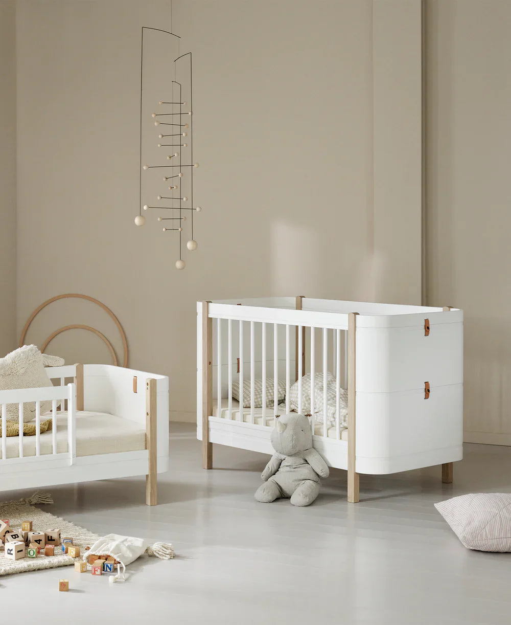 Wood Mini+ cot bed with junior kit in white and oak, featuring a compact design and natural wood finish from Oliver Furniture.