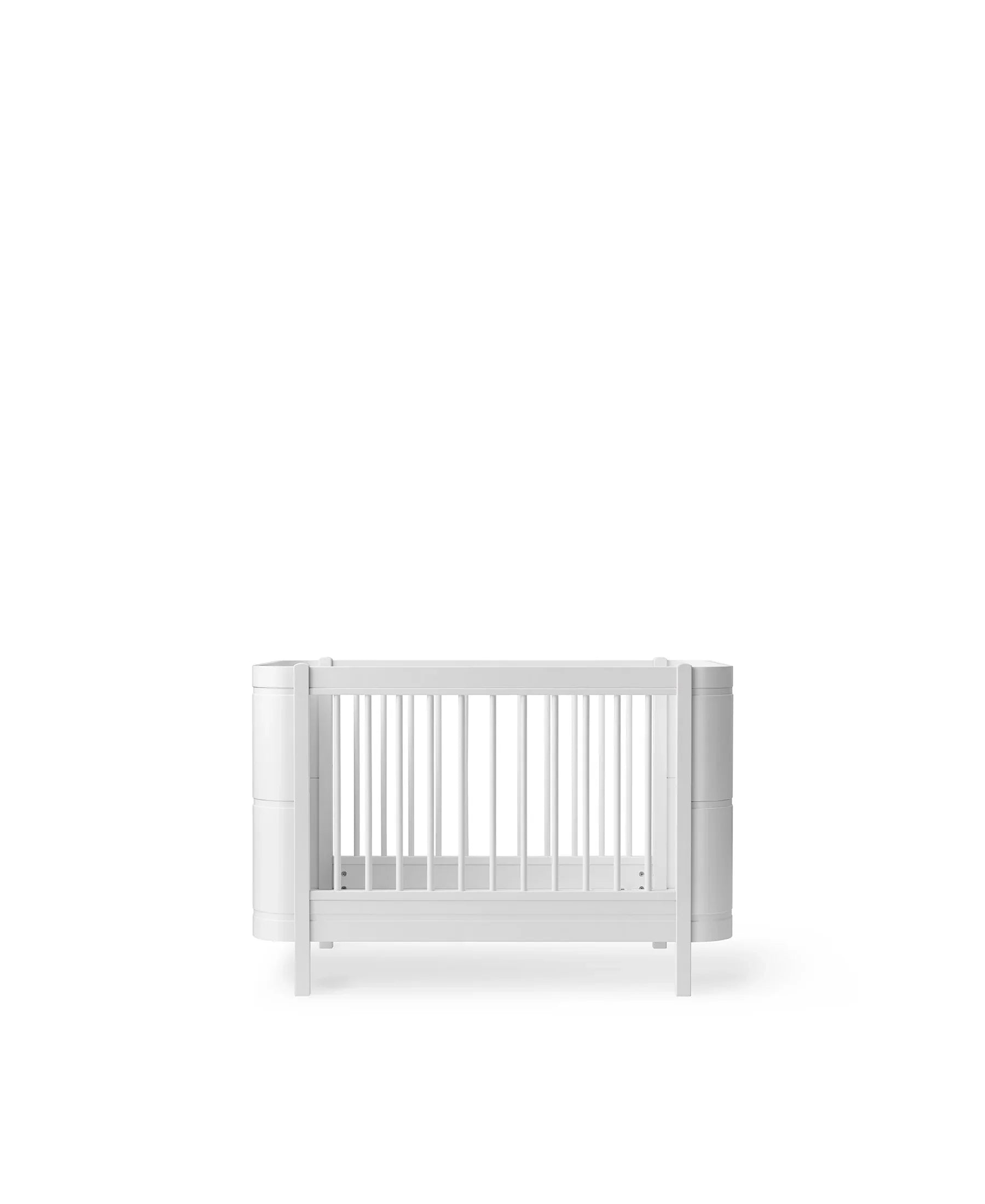White Oliver Furniture Wood Mini+ Cot Bed with Junior Kit, showcasing a compact wooden children's bed with safety rails and a minimalist design.