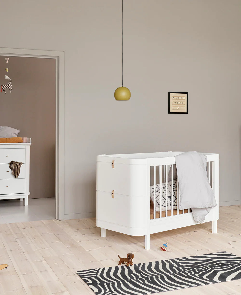 White Oliver Furniture Wood Mini+ Cot Bed with Junior Kit, showcasing a compact wooden baby cot with convertible design.