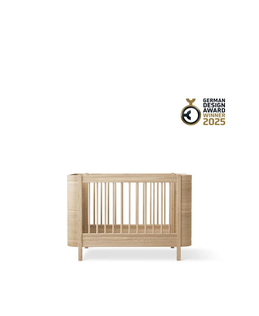 Wood Mini+ Cot Bed with Junior Kit in oak by Oliver Furniture, showing the convertible mini crib and bed with natural wood finish.