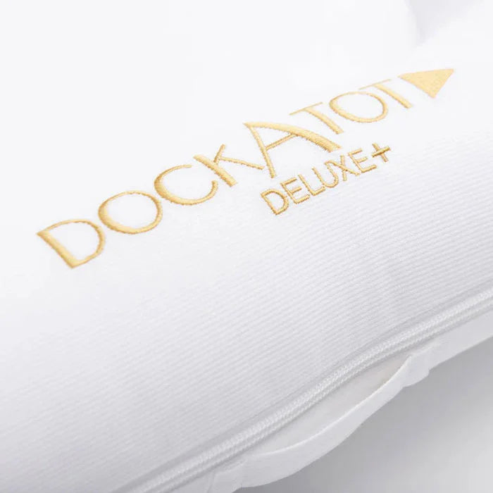 Pristine white Dock-A-Tot Deluxe+ Baby Dock for 0-8 months, soft fabric with cushioned sides, perfect for safe resting and play.
