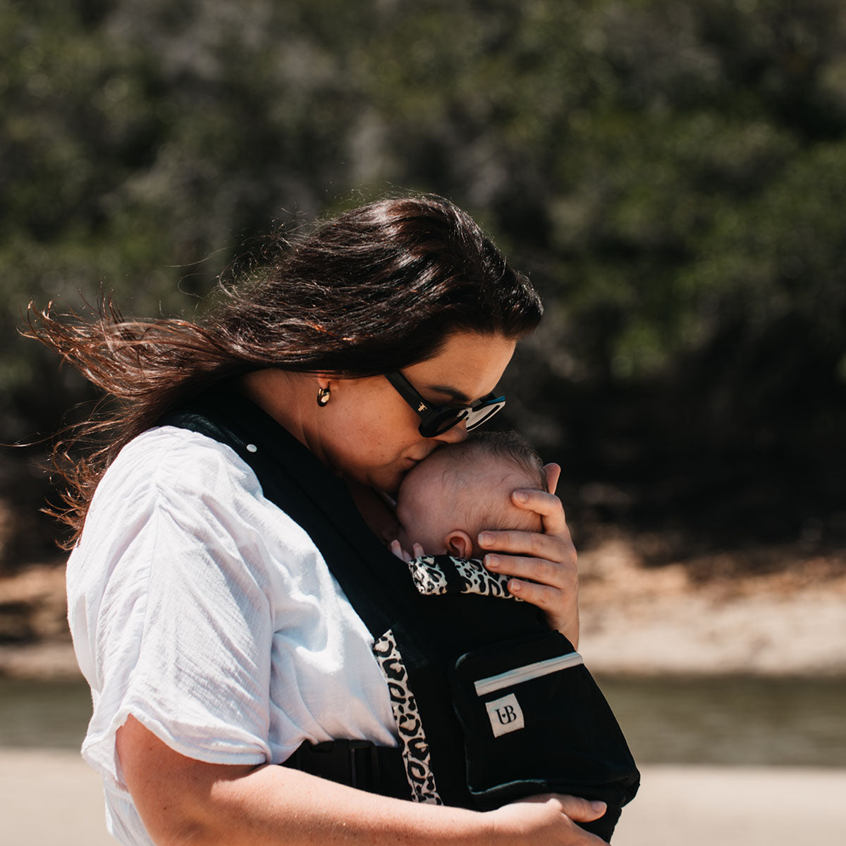 Mom kissing baby's head in the Ubuntu Baba Stage 1 Wildling baby carrier