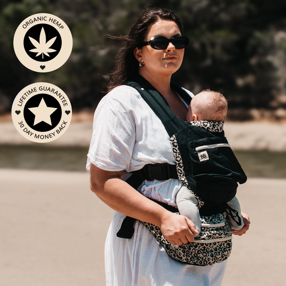 Mom wearing the Ubuntu Baba Stage 1 Wildling baby carrier, black with leopard print trim, with baby facing inward