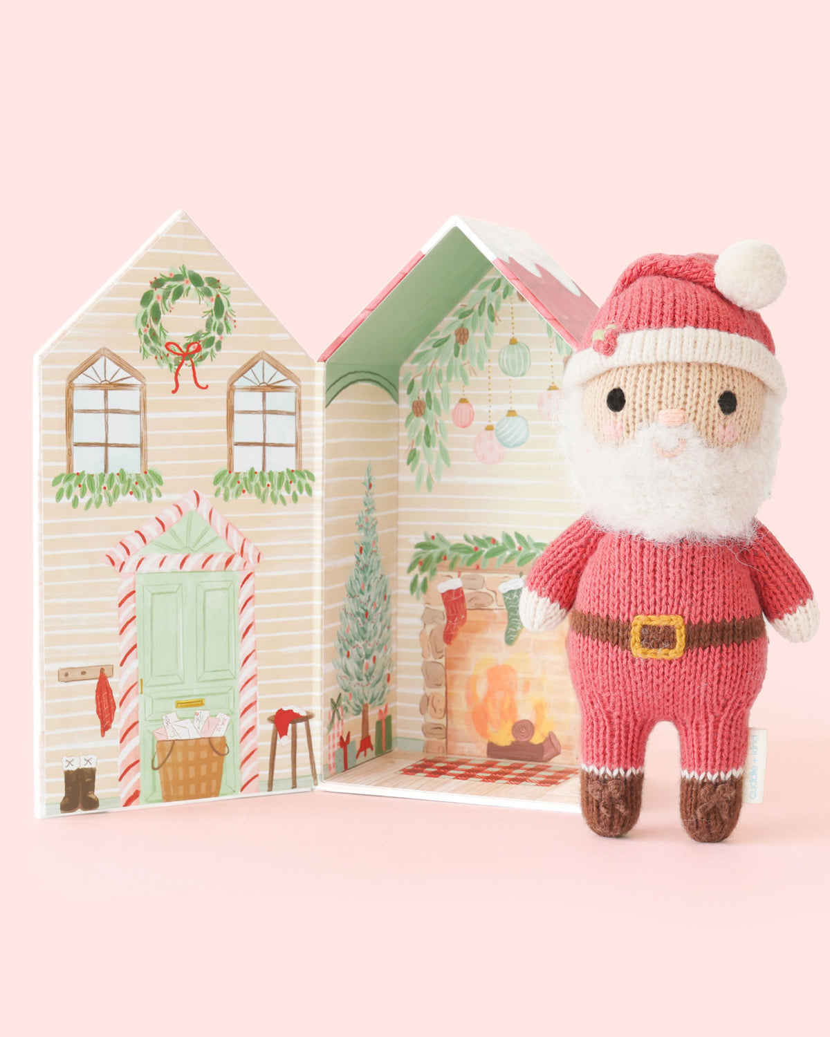 Small plush Tiny Santa toy from Cuddle + Kind with red hat and white beard, soft and cuddly for children.