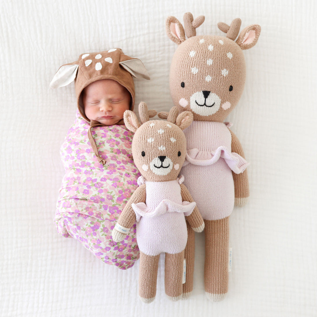 Violet the Fawn shown in both sizes beside a swaddled baby - Cuddle + Kind