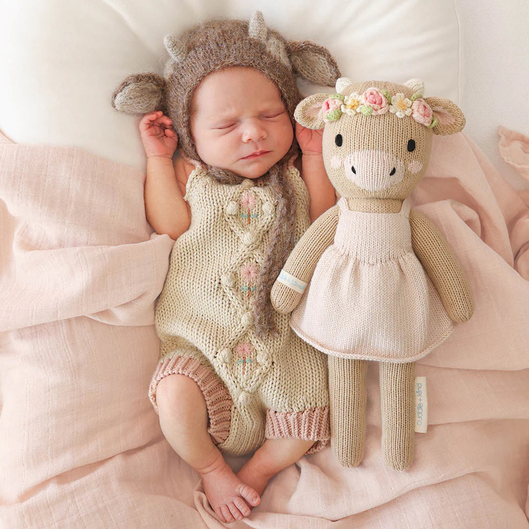 Amelia the Cow plush toy by Cuddle + Kind with soft white fur, black spots, and a gentle expression, perfect for cuddling.
