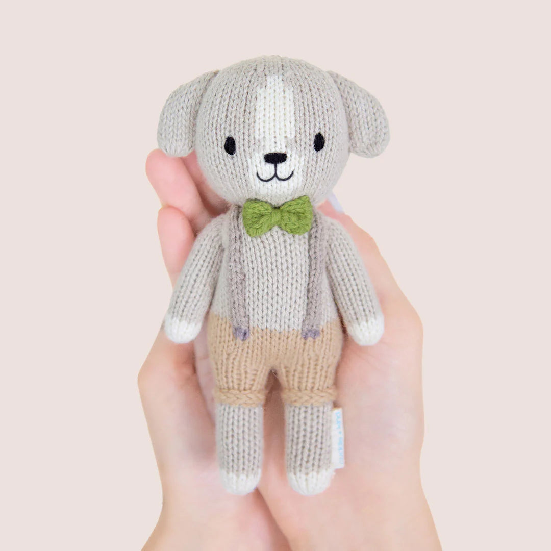 Tiny Noah the Dog from Cuddle + Kind, a soft plush toy featuring a cute brown and white dog with floppy ears and detailed fur.