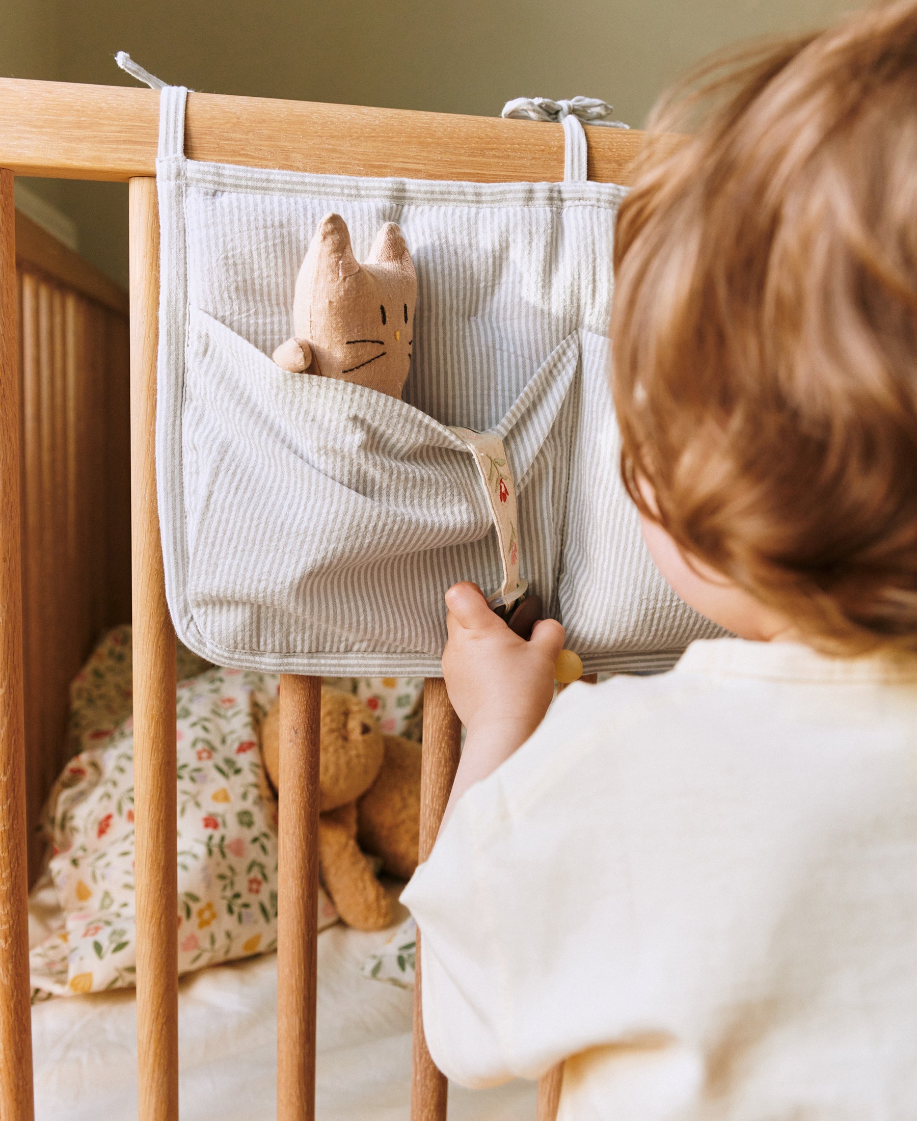 Dear April Polly Bed Pocket in Dew Stripe, styled on a cot.