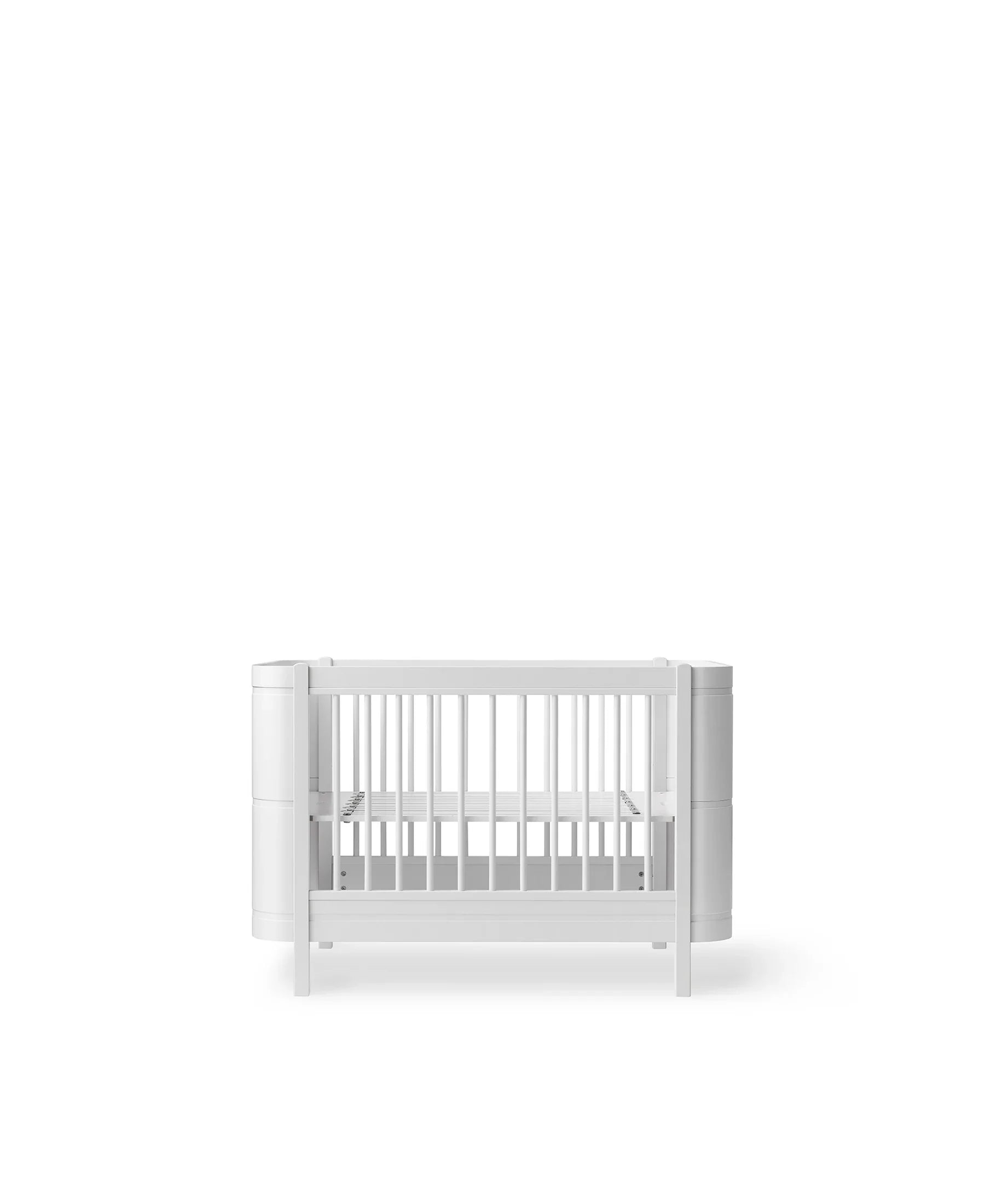 White Oliver Furniture Wood Mini+ Cot Bed with Junior Kit, showcasing the compact wooden baby bed with safety rails and modern design.