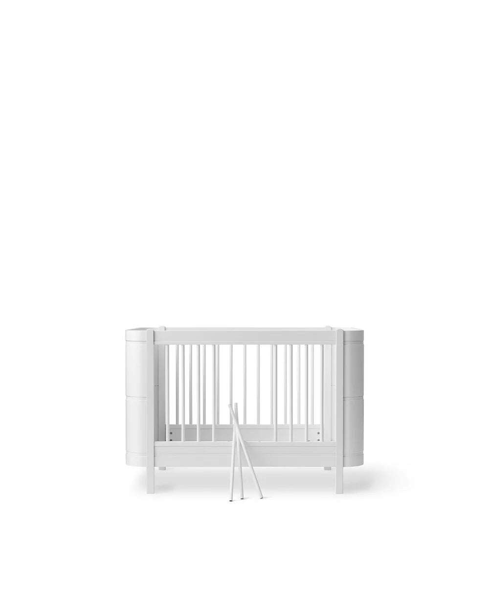 White Oliver Furniture Wood Mini+ Cot Bed with Junior Kit, showcasing the compact, stylish children's bed with safety rails.
