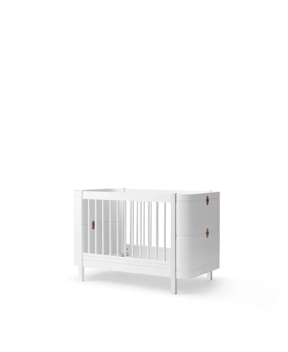 White Oliver Furniture Wood Mini+ Cot Bed with Junior Kit, a compact and sturdy children's furniture piece with safety rails.