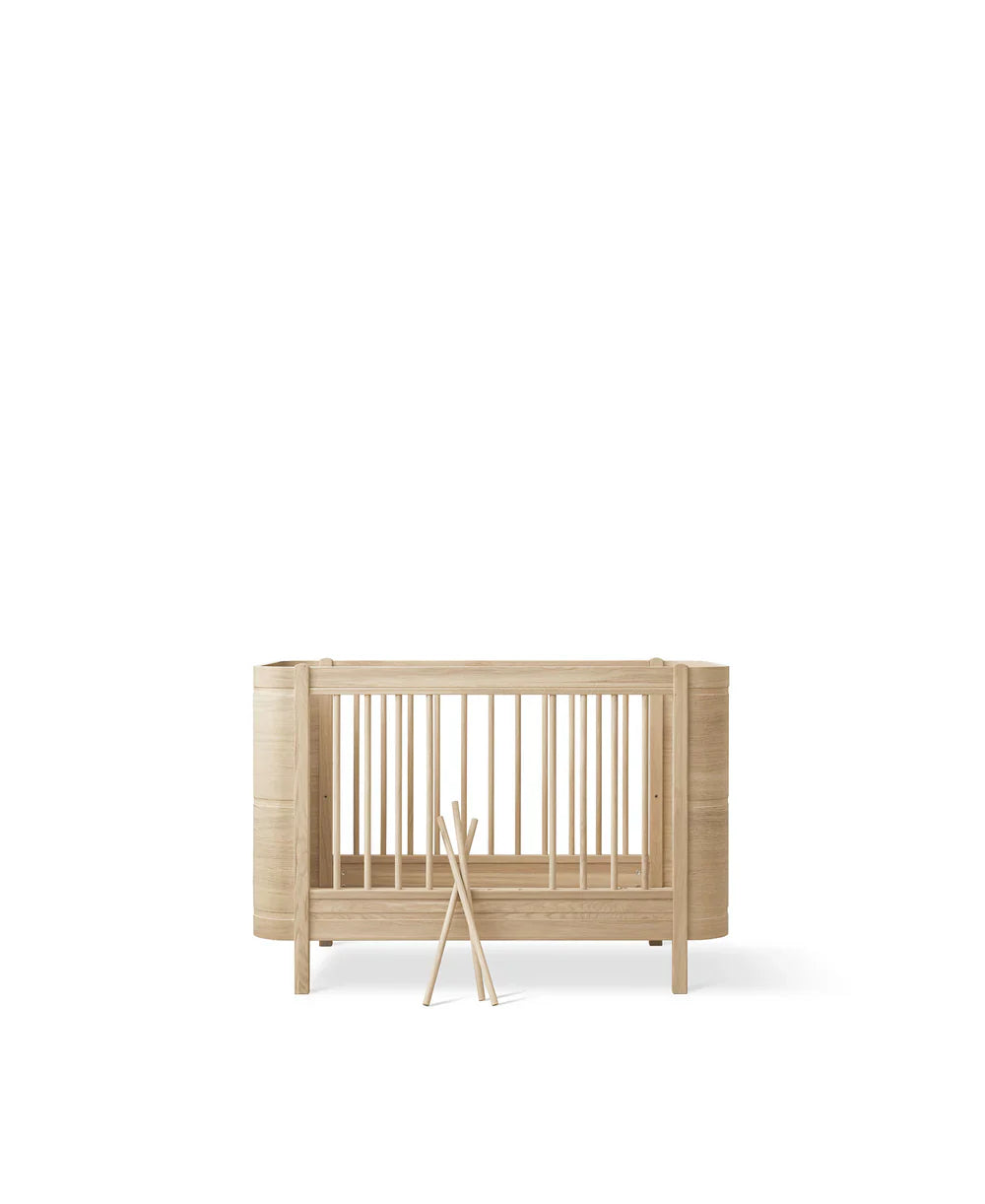 Wood Mini+ cot bed with junior kit in oak wood by Oliver Furniture, showing smooth wooden frame and adjustable components.