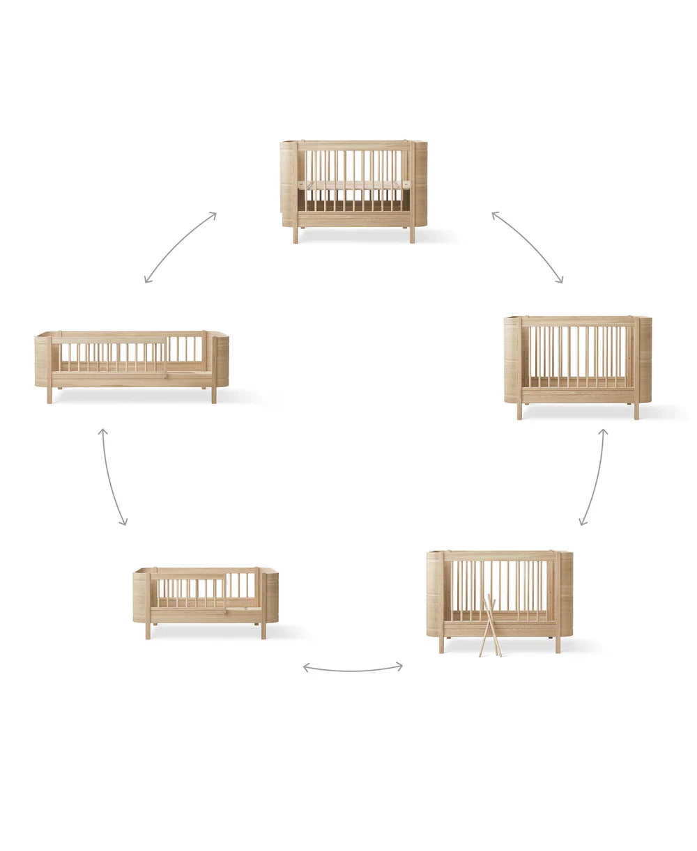 Oliver Furniture Wood Mini+ Cot Bed in white and oak with junior kit, showing a compact, stylish wooden baby bed for versatile use.