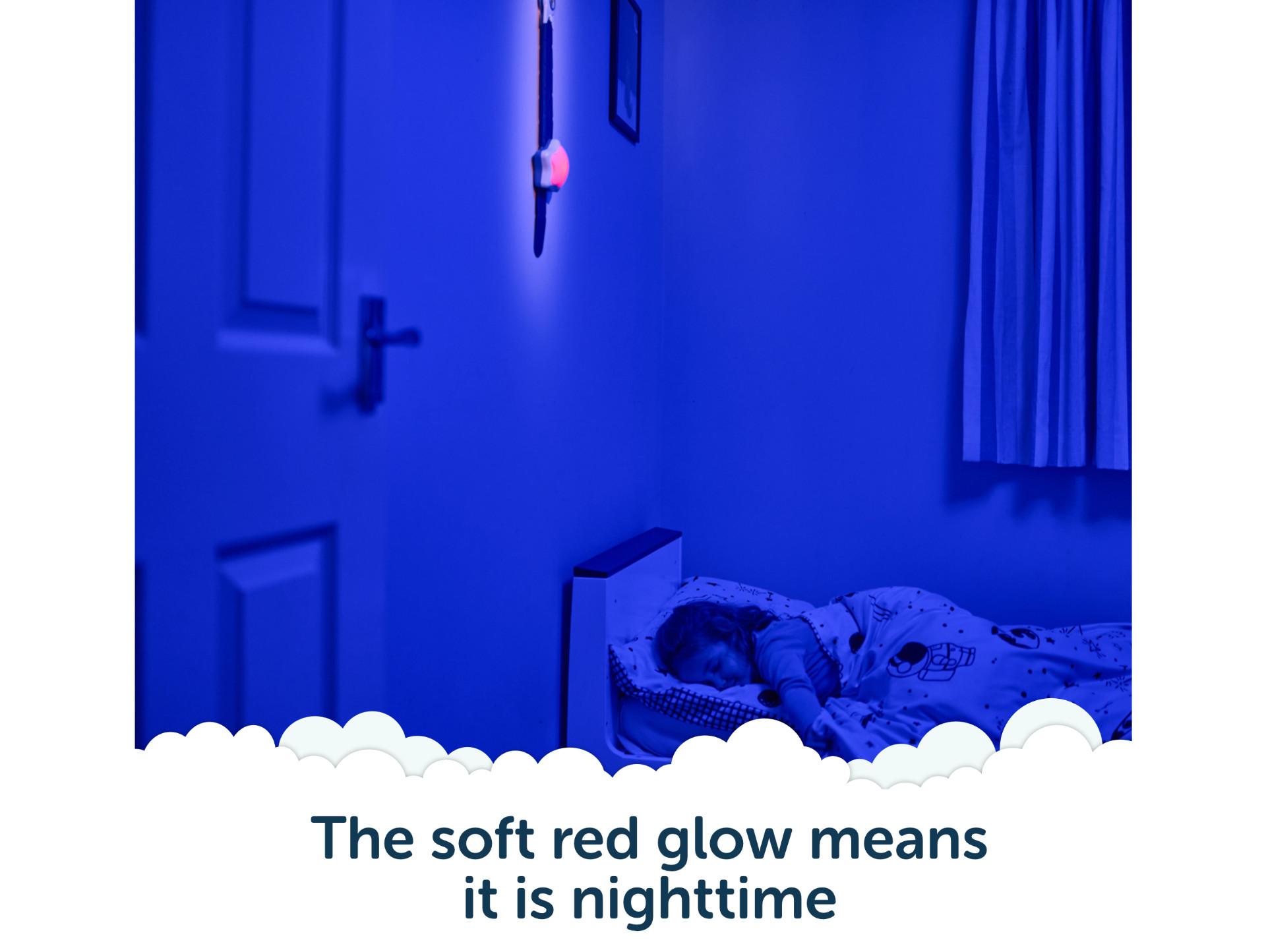 Child asleep with Rising Star glowing red on the wall - the soft red glow means it is night time.