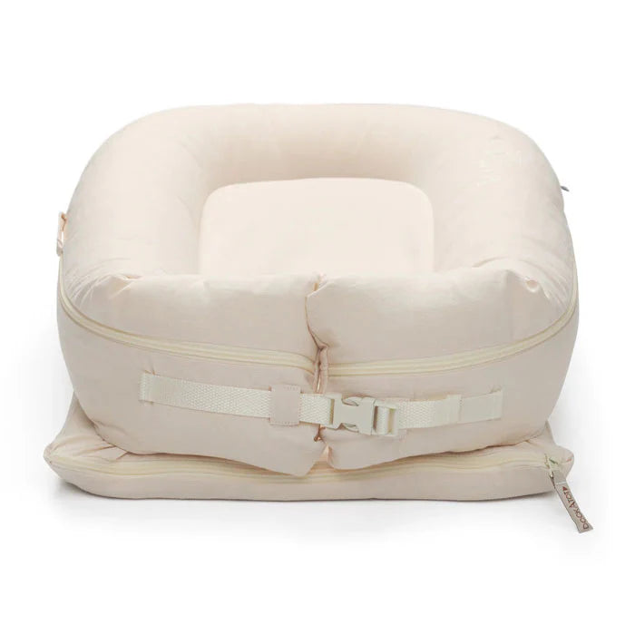 Dock-A-Tot Deluxe+ Dock for babies 0-8 months in Sand Chambray, showing soft fabric and secure baby rest surface.